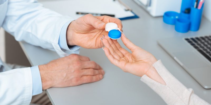 cropped shot of ophthalmologist giving contact lens to patient in clinic